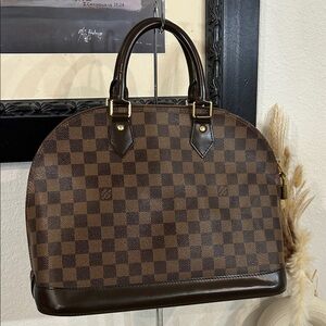 Louis Vuitton  Alma top handle bag features the iconic Damier Ebene Bag +COA